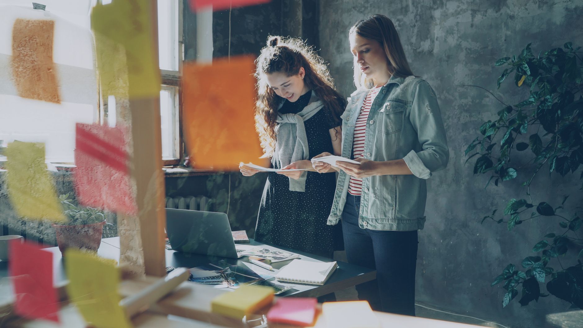 Two people at a laptop with sticky notes, writing a runbook